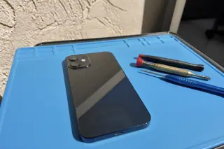 Smartphone with a new back glass panel reflecting sunlight on a repair mat in Phoenix, AZ.