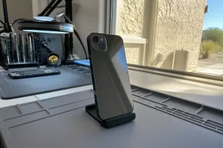 Smartphone with a finished back glass repair resting on a workbench in Phoenix, AZ, with bright sunlight and stucco walls.