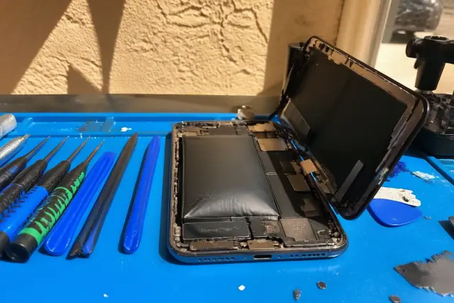 Opened smartphone with a swollen battery and heat damage on a workstation in Phoenix, AZ.