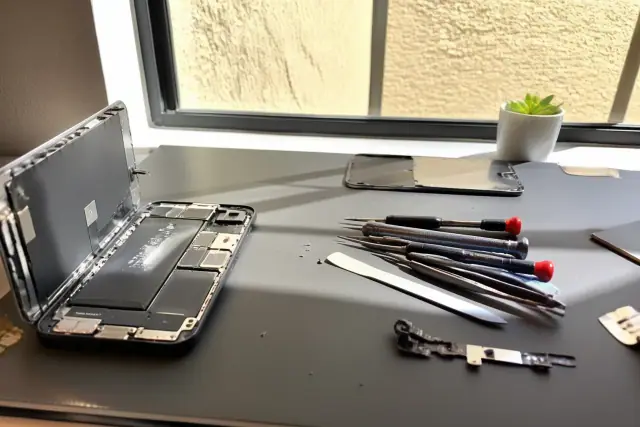 Technician repairing a smartphone charging port on a workbench in Phoenix, AZ.