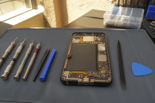 Technician repairing a smartphone charging port at a workstation in Phoenix, AZ.