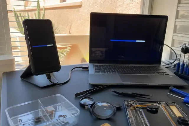 Smartphone connected to a laptop for data backup on an anti-static workbench in Phoenix, AZ.