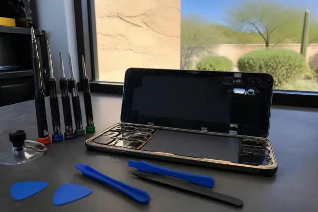 Open smartphone with exposed internal components on a workbench in a Phoenix, AZ repair shop.