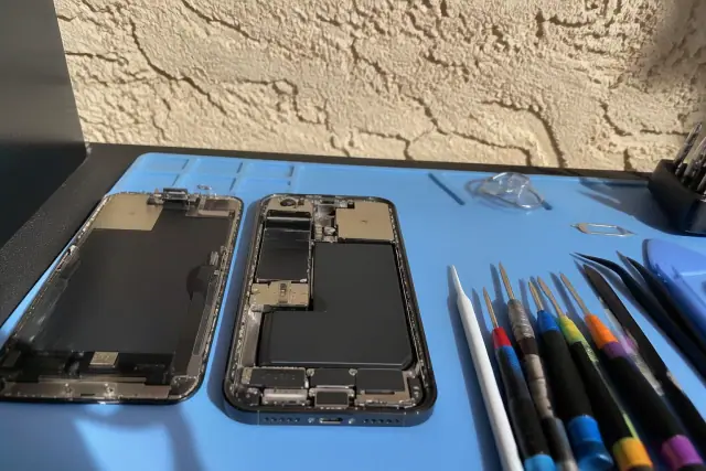 Opened smartphone with internal components on a workbench during a charging port repair in Phoenix, AZ.
