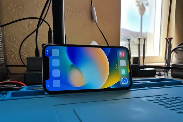 Smartphone screen repair testing on a workbench in a sunny Phoenix, AZ workshop.