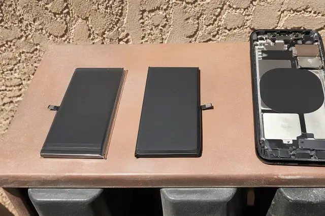 Two phone batteries and an open smartphone chassis on a workbench in Phoenix, AZ.