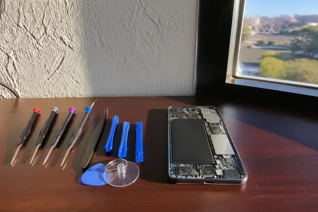 Technician repairing an open smartphone with professional tools on a workstation in Phoenix, AZ.