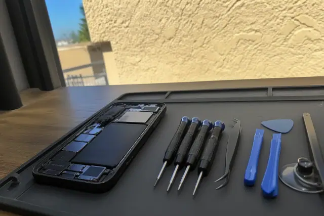 Opened smartphone with exposed internal components and repair tools on a workstation in Chandler, AZ.