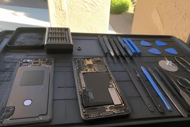 Opened smartphone with exposed internal components and repair tools on a workstation in Gilbert, AZ.
