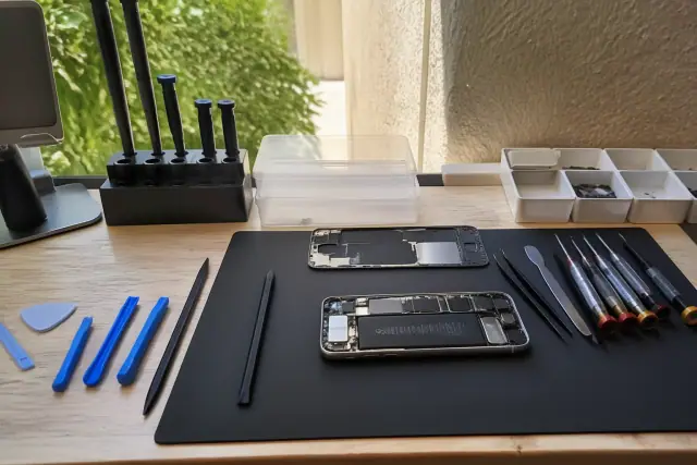 Smartphone with internal components exposed on a workbench with repair tools in Paradise Valley, AZ.