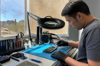 Technician wiping down a Google Pixel on an organized workbench with tools in a Phoenix, AZ workshop.