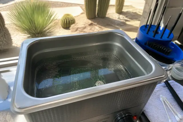 A circuit board being cleaned in an ultrasonic bath for Google Pixel water damage repair in Phoenix, AZ.