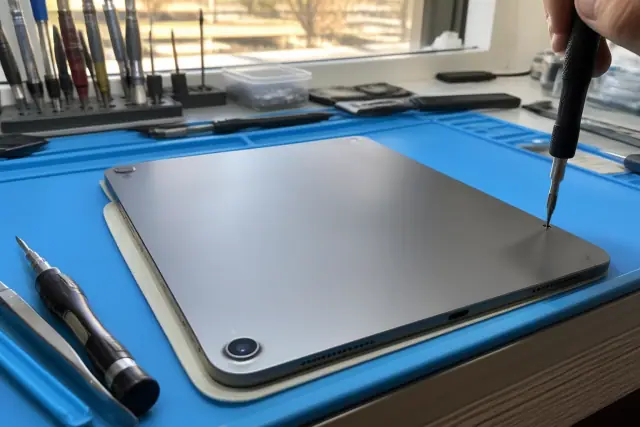 Technician using a precision screwdriver to fasten screws on an iPad during a repair in Phoenix, AZ.
