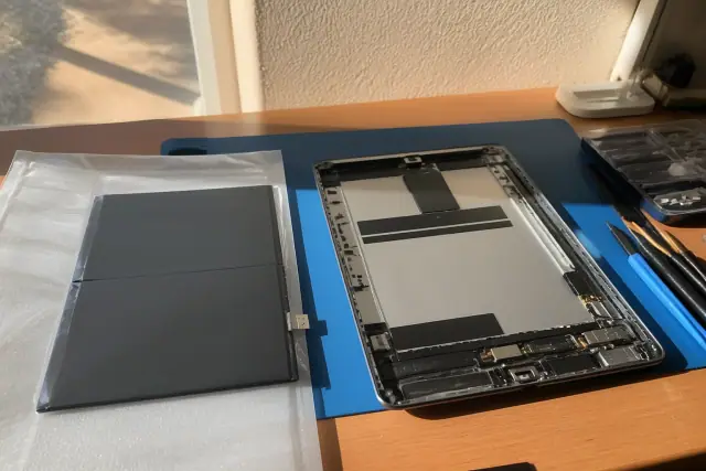 New battery being installed into an open iPad on a workbench in Phoenix, AZ.