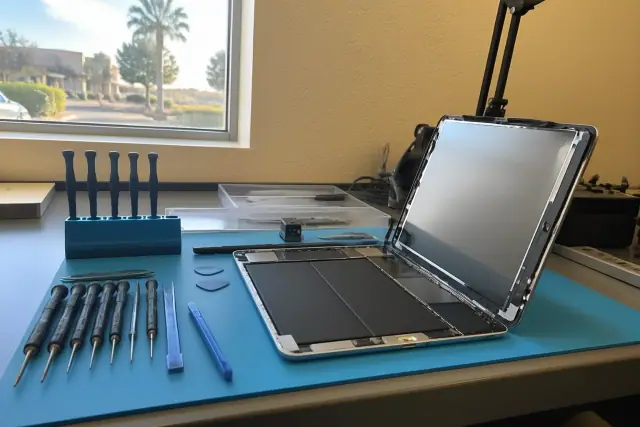 Technician repairing an opened smartphone with professional tools at a workstation in Mesa, AZ.