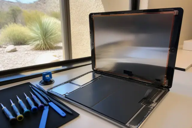 An iPad undergoing repair on a workbench in Paradise Valley, AZ, showing internal components and ribbon cables.