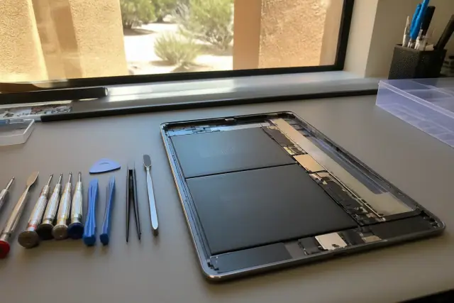 Technician repairing an opened smartphone with professional tools at a workstation in Gilbert, AZ.