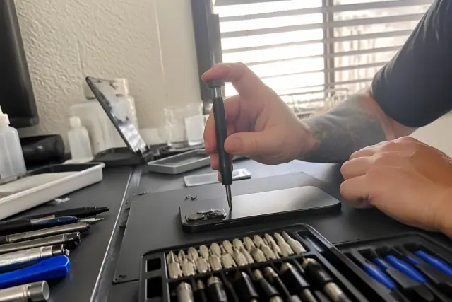 iPhone back glass repair in progress on a workbench in Phoenix, AZ.