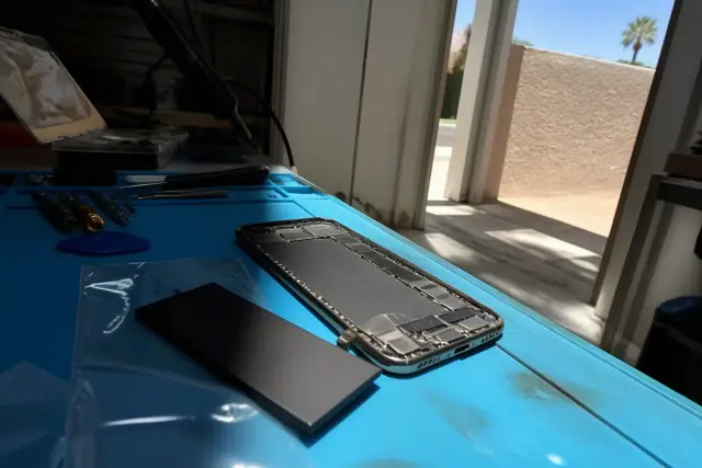 A smartphone battery replacement kit and open phone chassis in a workshop in Phoenix, AZ.