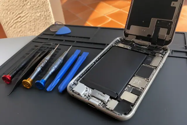 Opened iPhone with exposed internal components and lightning port for repair on a workstation in Phoenix, AZ.