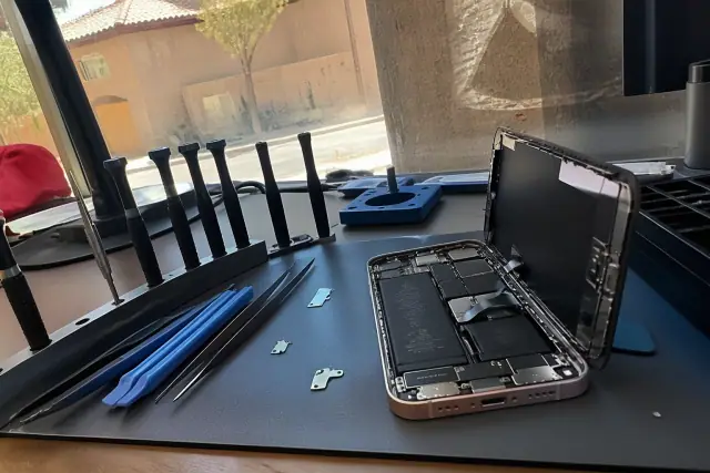 Opened smartphone with internal components and repair tools on a workbench in Avondale, AZ.