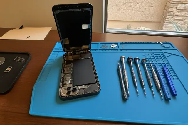 An open smartphone with internal components on a repair workstation in Goodyear, AZ.