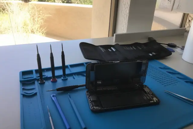 Professional repair tools and an open smartphone on a workbench in Phoenix, AZ.