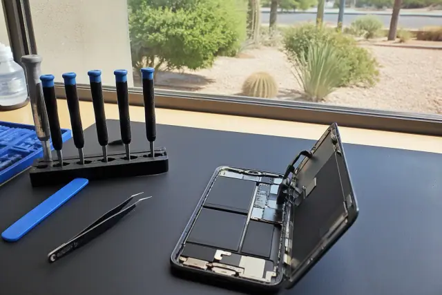 Opened smartphone with internal components and tools on a workstation in Tempe, AZ.