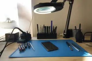 Repaired smartphone on a static-safe mat with precision screwdrivers at a workbench in Phoenix, AZ.