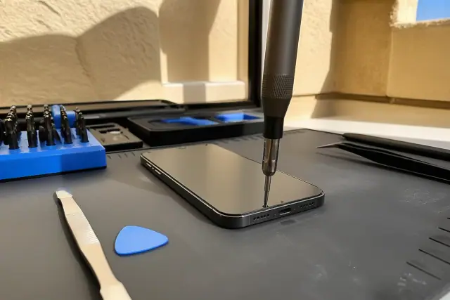 A technician repairing a smartphone with precision tools in a workshop in Phoenix, AZ.