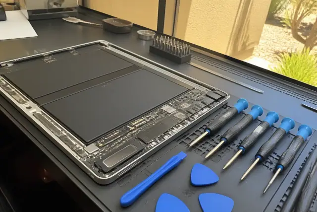 Opened smartphone with exposed internal components and charging ports at a repair workstation in Phoenix, AZ.