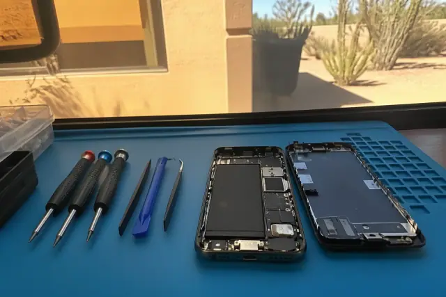 Smartphone charging port repair in progress on an organized workbench in Phoenix, AZ.