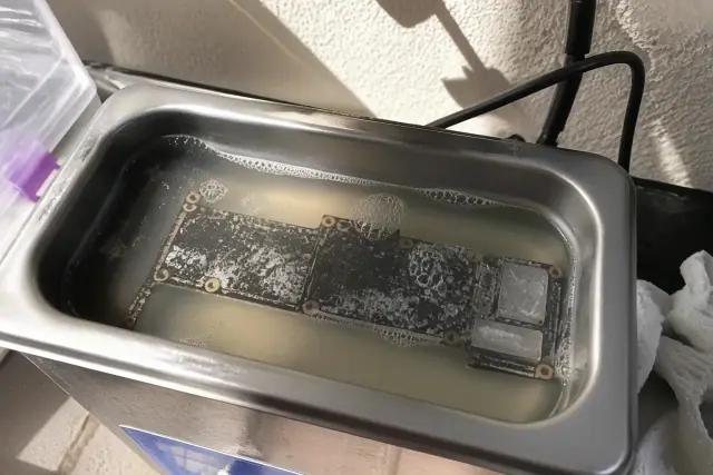 Circuit board submerged in an ultrasonic cleaner for liquid damage repair in a Phoenix, AZ workshop.