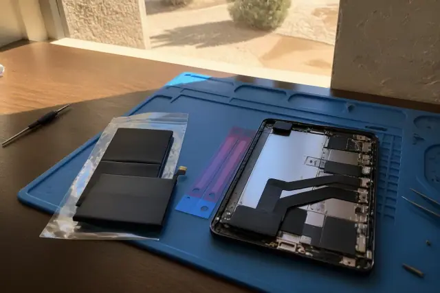 Replacement phone battery and open device on an anti-static mat during a repair in Gilbert, AZ.