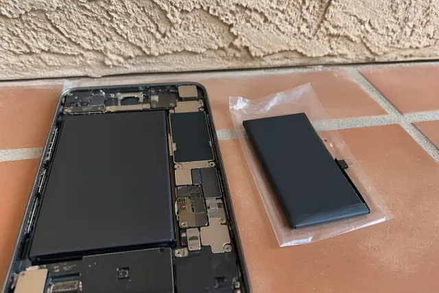 Replacement phone battery next to an open device on a terracotta floor in Mesa, AZ.