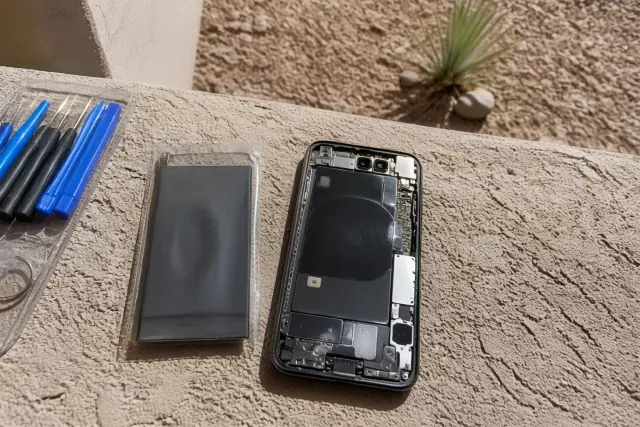 A replacement battery next to an open smartphone chassis during a repair in Goodyear, AZ.