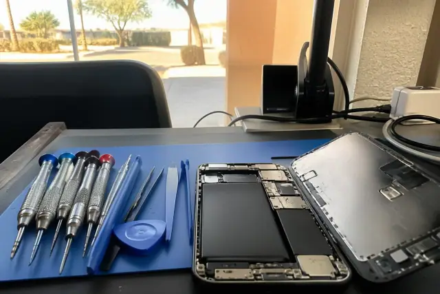 Professional tools and an opened smartphone on a workbench in a repair shop in Phoenix, AZ.