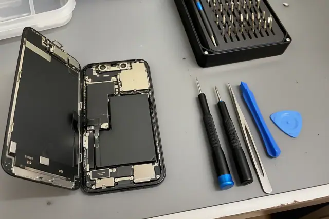 An opened smartphone with exposed internal components and repair tools on a workstation in Goodyear, AZ.