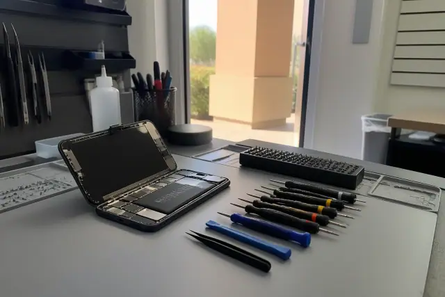 An open smartphone with internal components on a repair workstation with tools in a shop in Chandler, AZ.