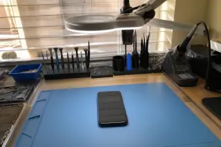 Finished smartphone on a workbench with a soldering station and tools in Phoenix, AZ.