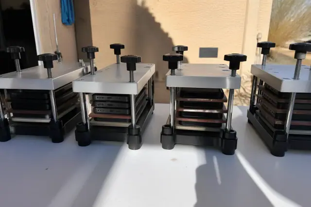 Mobile devices held in pressure clamps for screen adhesive curing at a jobsite in Phoenix, AZ.