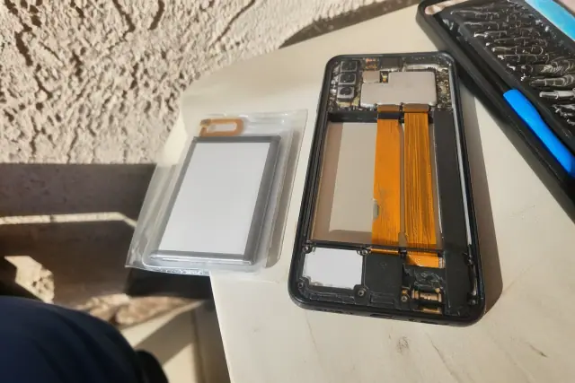 A replacement battery and open smartphone chassis during a repair on a stucco surface in Phoenix, AZ.