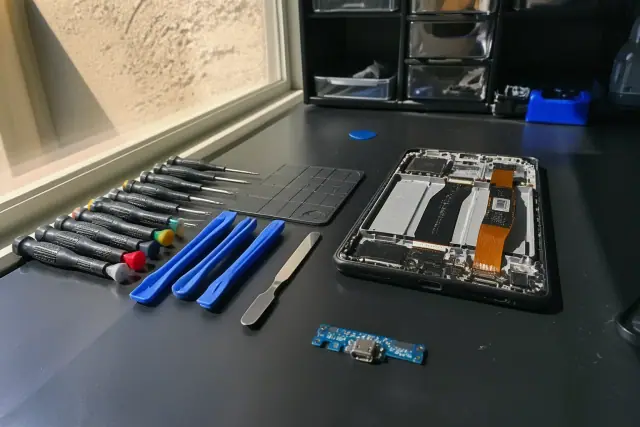 Samsung smartphone being repaired at a workbench in Phoenix, AZ, with internal components exposed and tools nearby.