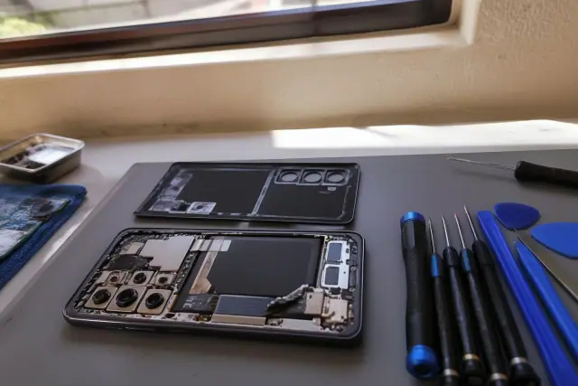 An opened Samsung smartphone with exposed internal parts being repaired at a workstation in Tempe, AZ.