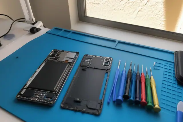 Technician repairing an open smartphone with professional tools on a workstation in Glendale, AZ.