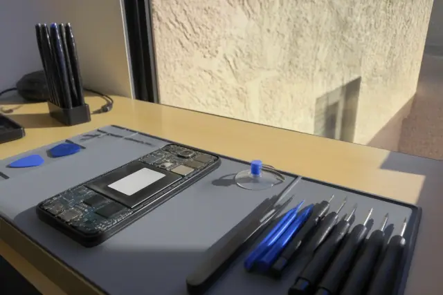Opened smartphone with internal components on an organized repair workstation in Phoenix, AZ.