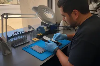 Technician inspecting a Samsung phone screen on an organized workbench in Phoenix, AZ.