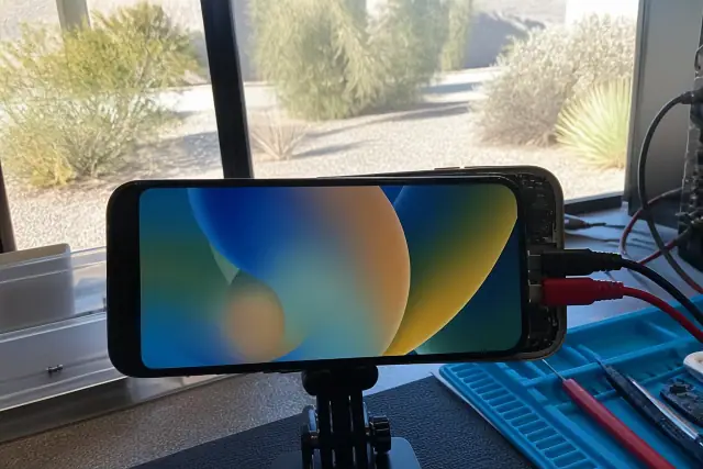 A smartphone showing a newly installed mobile device screen on a testing bench at a workshop in Phoenix, AZ.