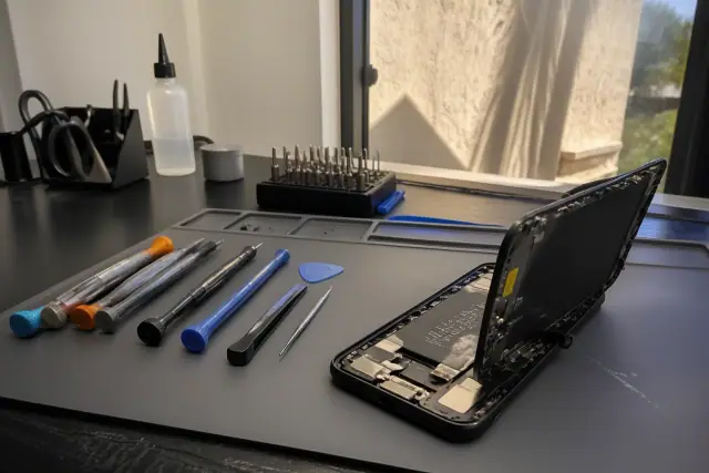 Opened smartphone with internal parts on a technician workbench in Phoenix, AZ.