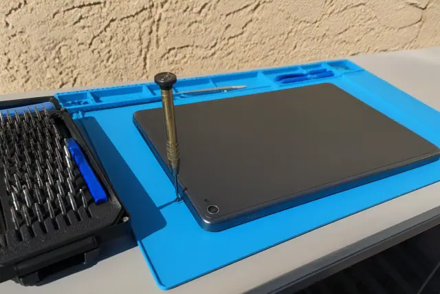 Precision repair tools and a tablet being reassembled on a stucco surface in Phoenix, AZ.